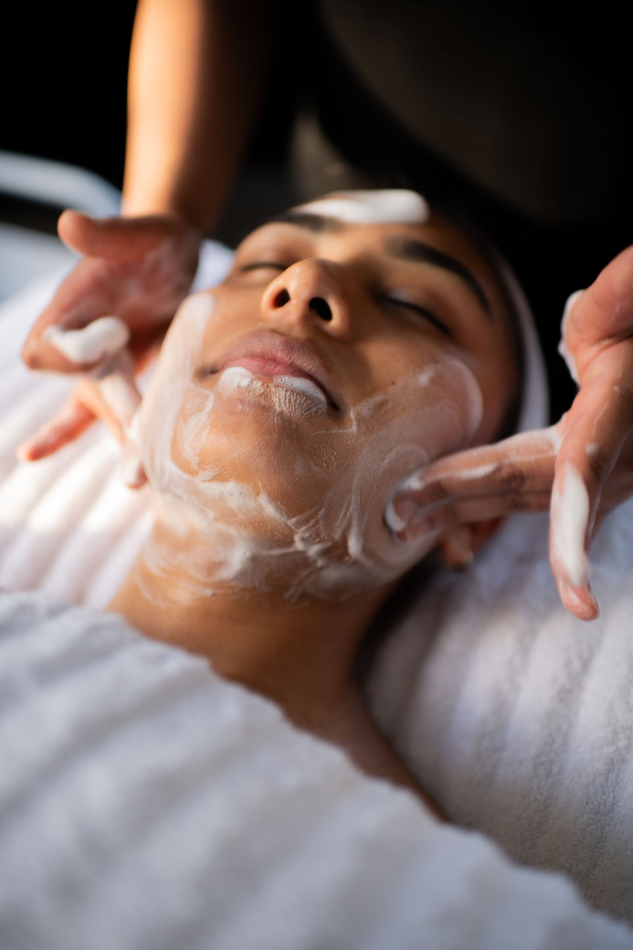 Therapist applying a creamy mask to a smiling client